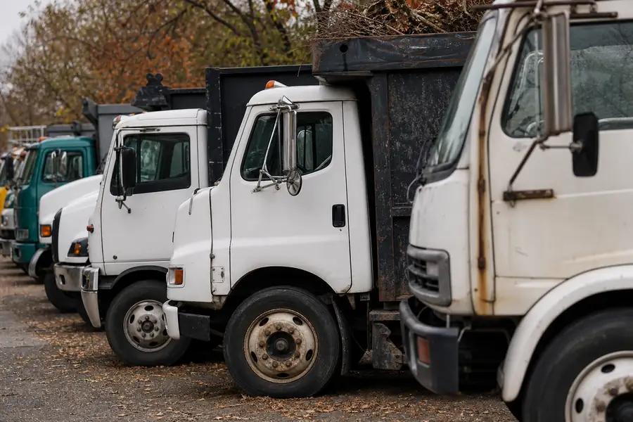Row of different junk removal trucks parked on a street