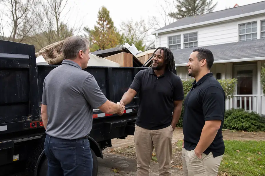 Homeowner thanking two junk removal crew members next to a loaded truck