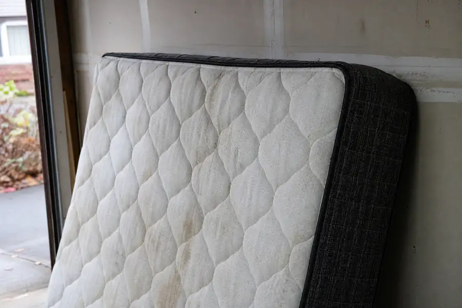 Mattress leaning against a garage wall ready for pickup