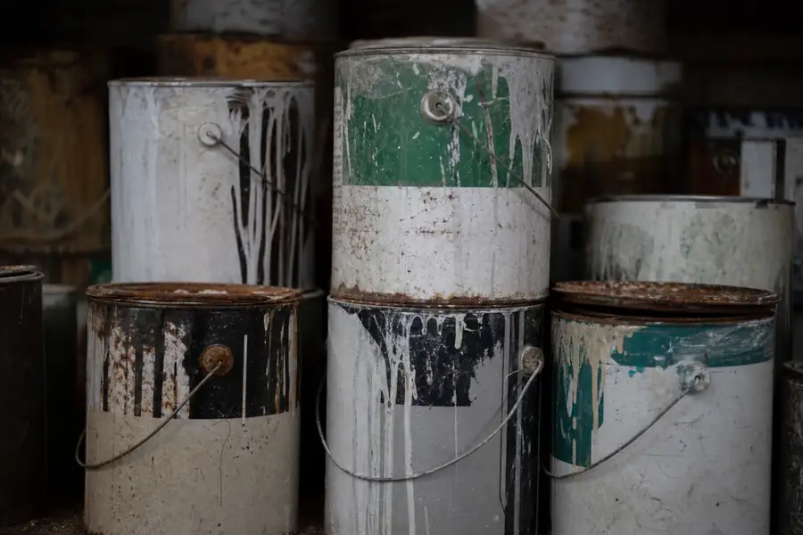 Stack of old paint cans on a garage shelf