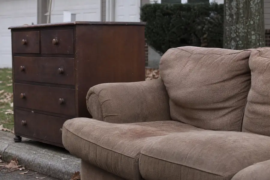 Sofa and dresser on a curb in front of a suburban house