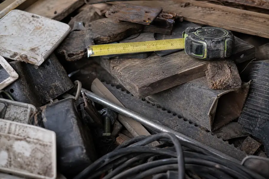 Pile of junk in a garage with a tape measure
