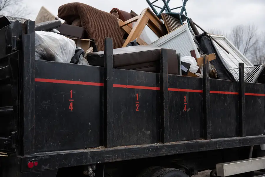 Junk removal truck bed marked into load fractions with junk inside